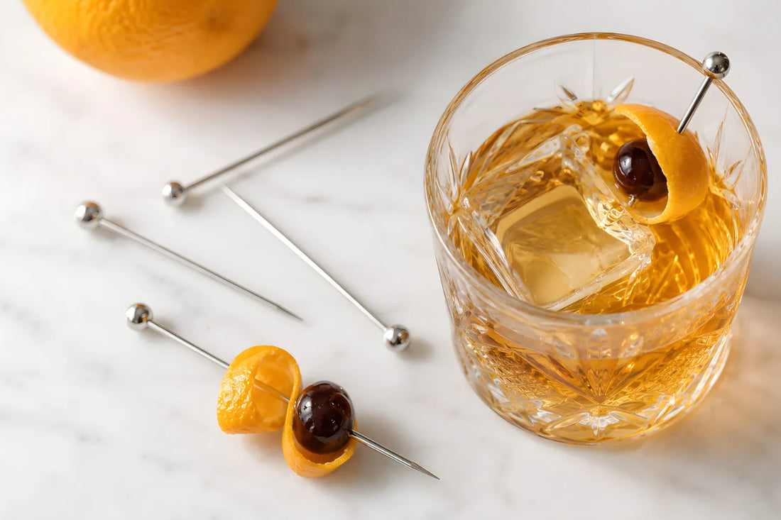 cocktail pick holding an orange peel and cherry garnish in an old fashioned