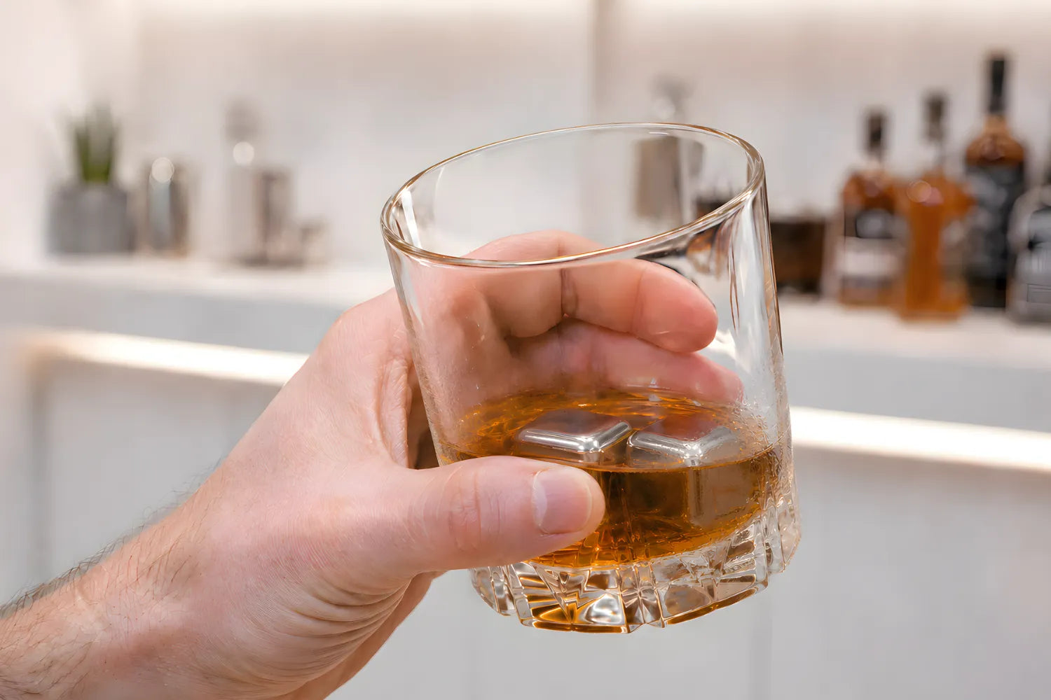holding a whiskey glass with stainless steel ice cubes