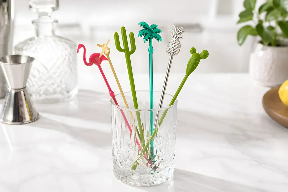 Plastic, bamboo, and metal swizzle sticks displayed in glasses