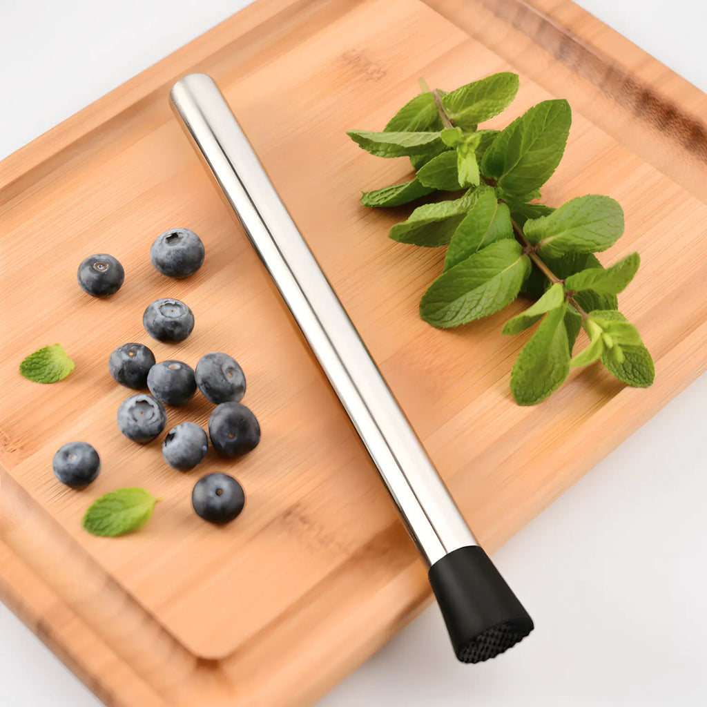 10 inch muddler next to berries and herbs