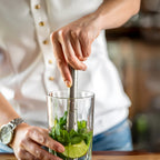 Bartender muddling mint with a rubber head muddler