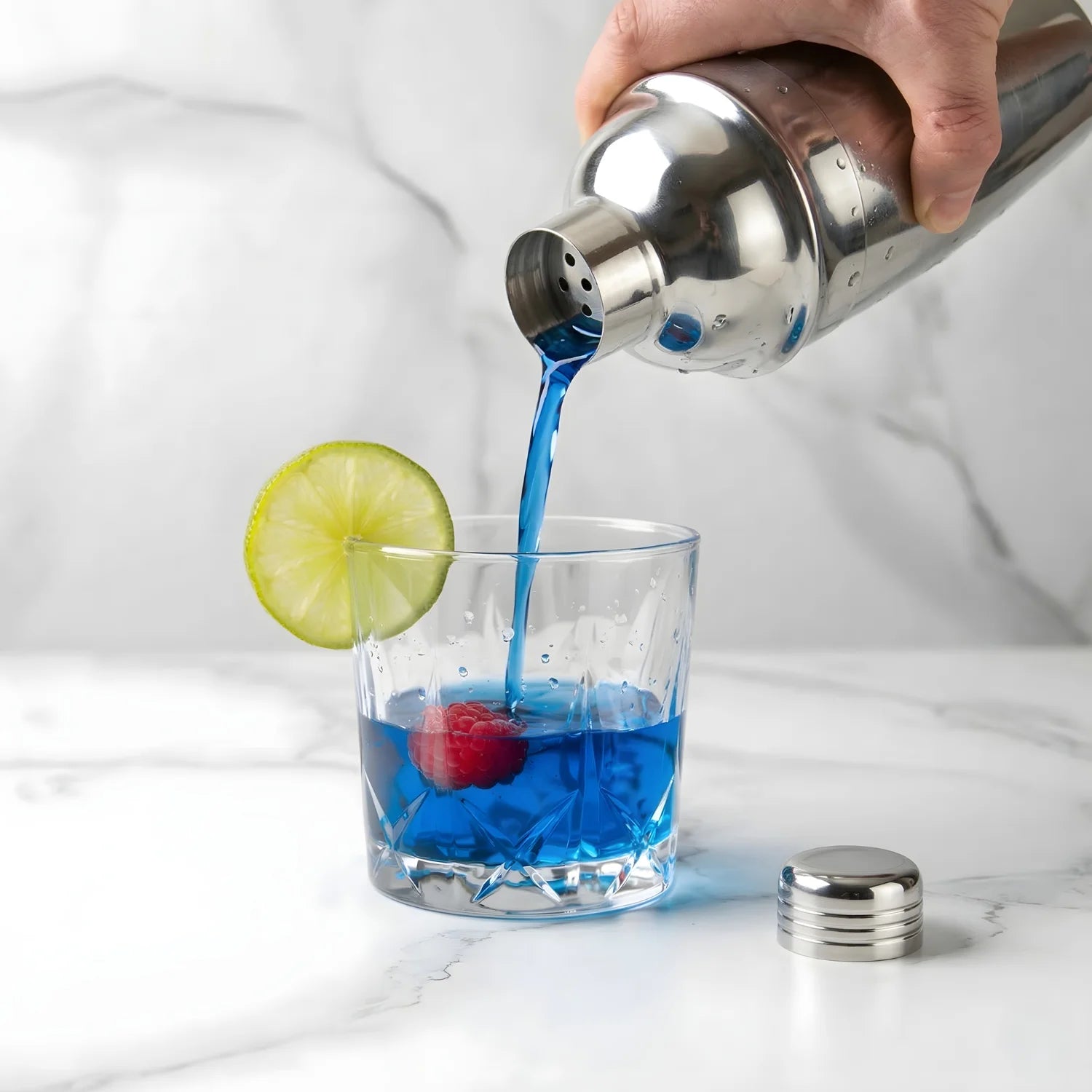 cobbler shaker pouring a cocktail into a glass