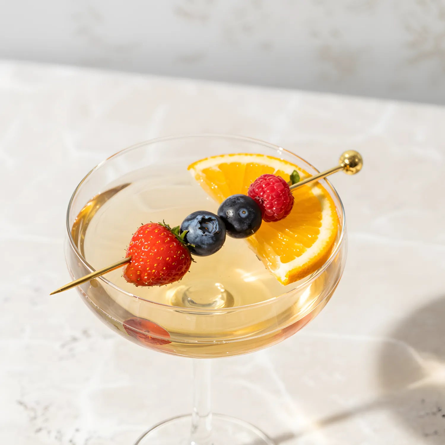 gold ball cocktail pick speared through berries