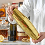 bartender shaking a gold Boston shaker at home bar