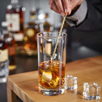 gold teardrop bar spoon is stirring in a glass