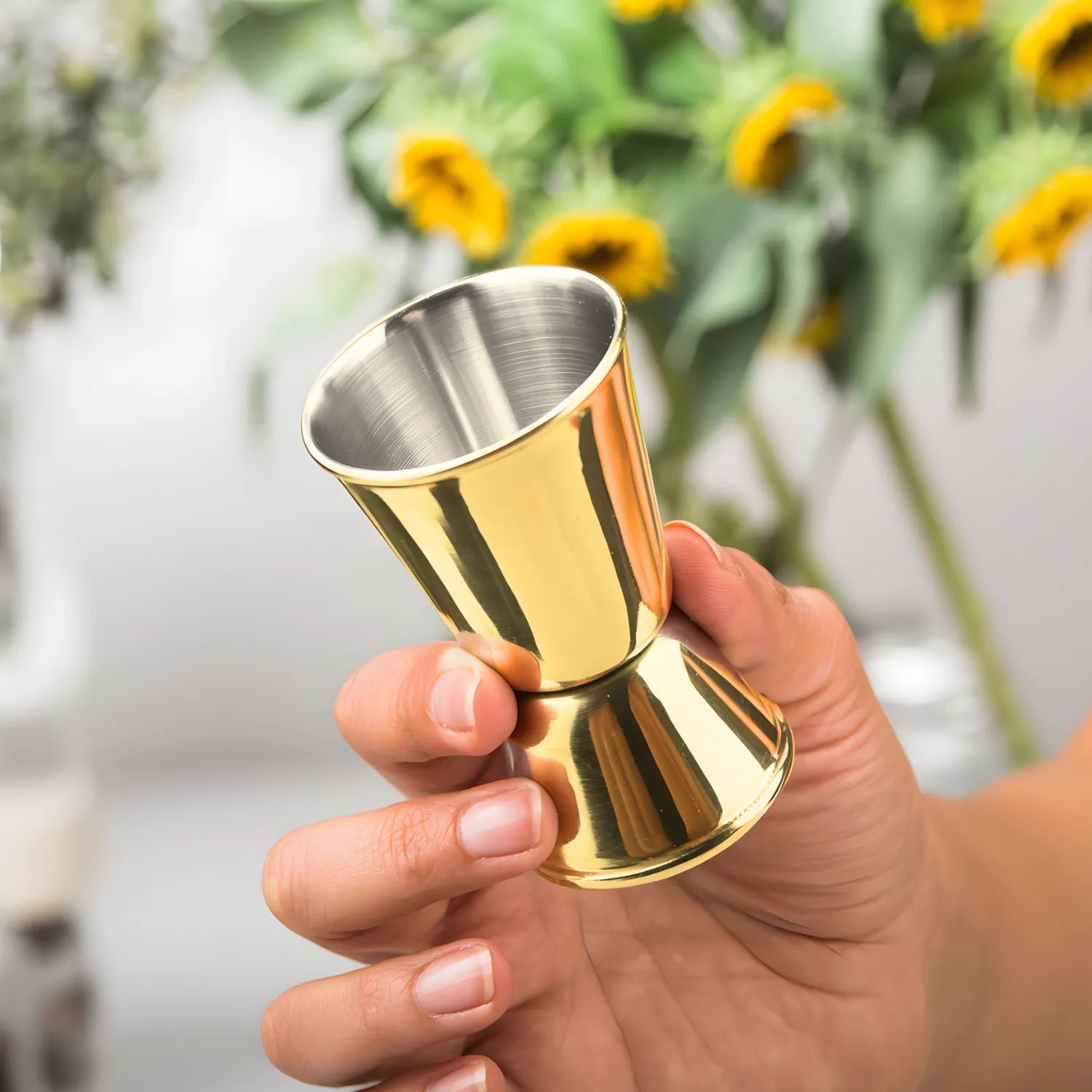 bartender holding a gold classic jigger in hand
