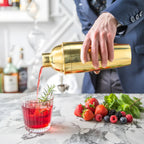 gold cobbler shaker pouring a cocktail into a glass