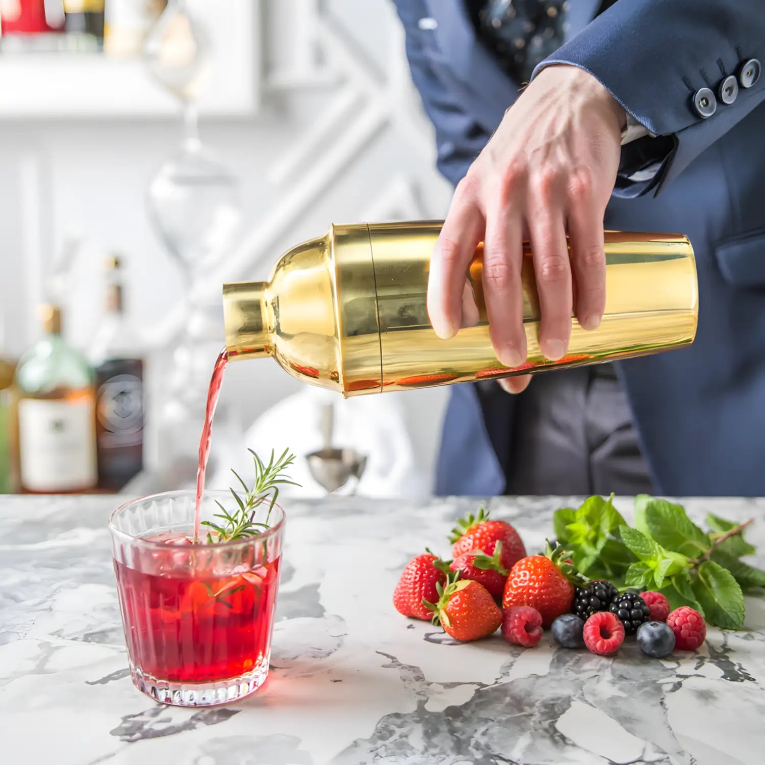 gold cobbler shaker pouring a cocktail into a glass