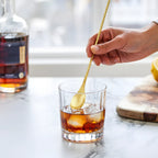 gold fork end bar spoon is stirring in a glass