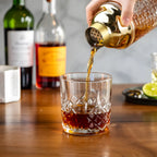 gold glass cocktail shaker pouring a cocktail into a glass