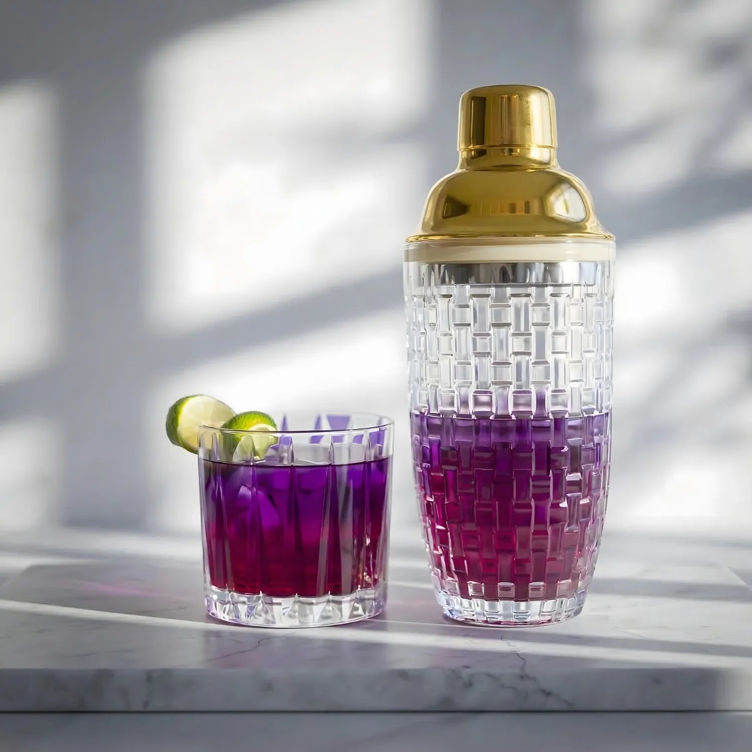 gold glass cocktail shaker placed next to a cocktail