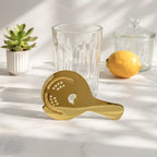 gold Hawthorne strainer on a home bar counter