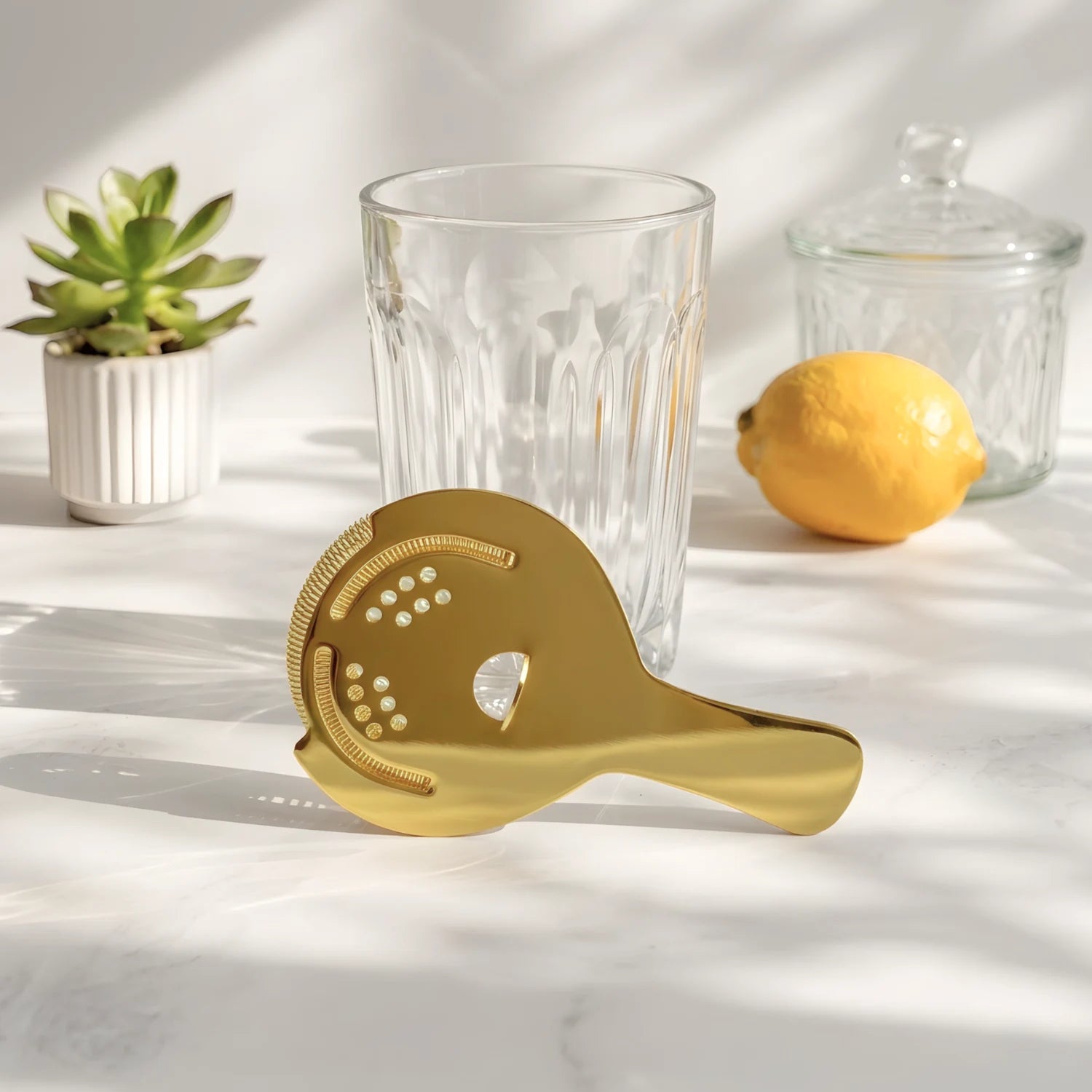 gold Hawthorne strainer on a home bar counter