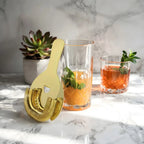 gold Hawthorne strainer next to a cocktail