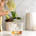 Bartender straining cocktail with a gold Hawthorne strainer