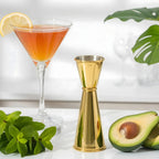gold Japanese jigger next to a cocktail