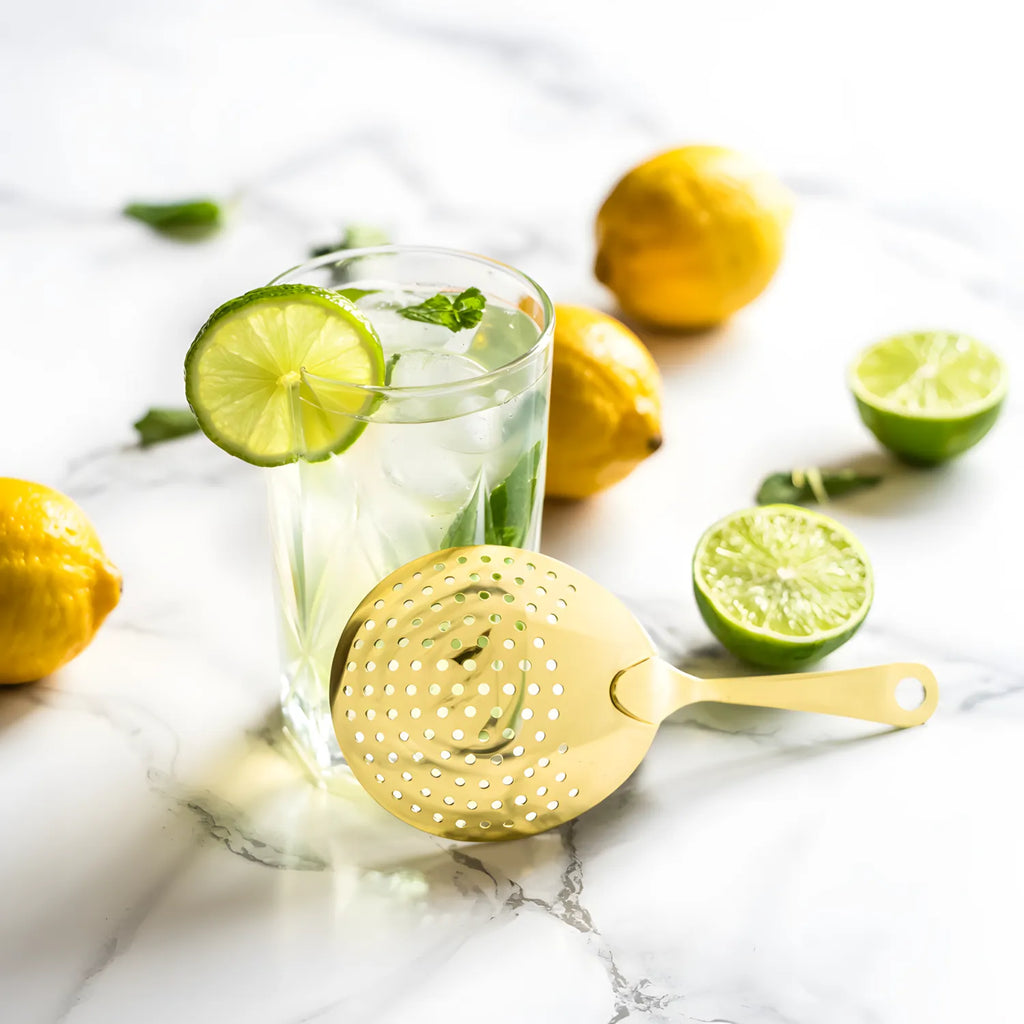 gold Julep strainer next to a cocktail