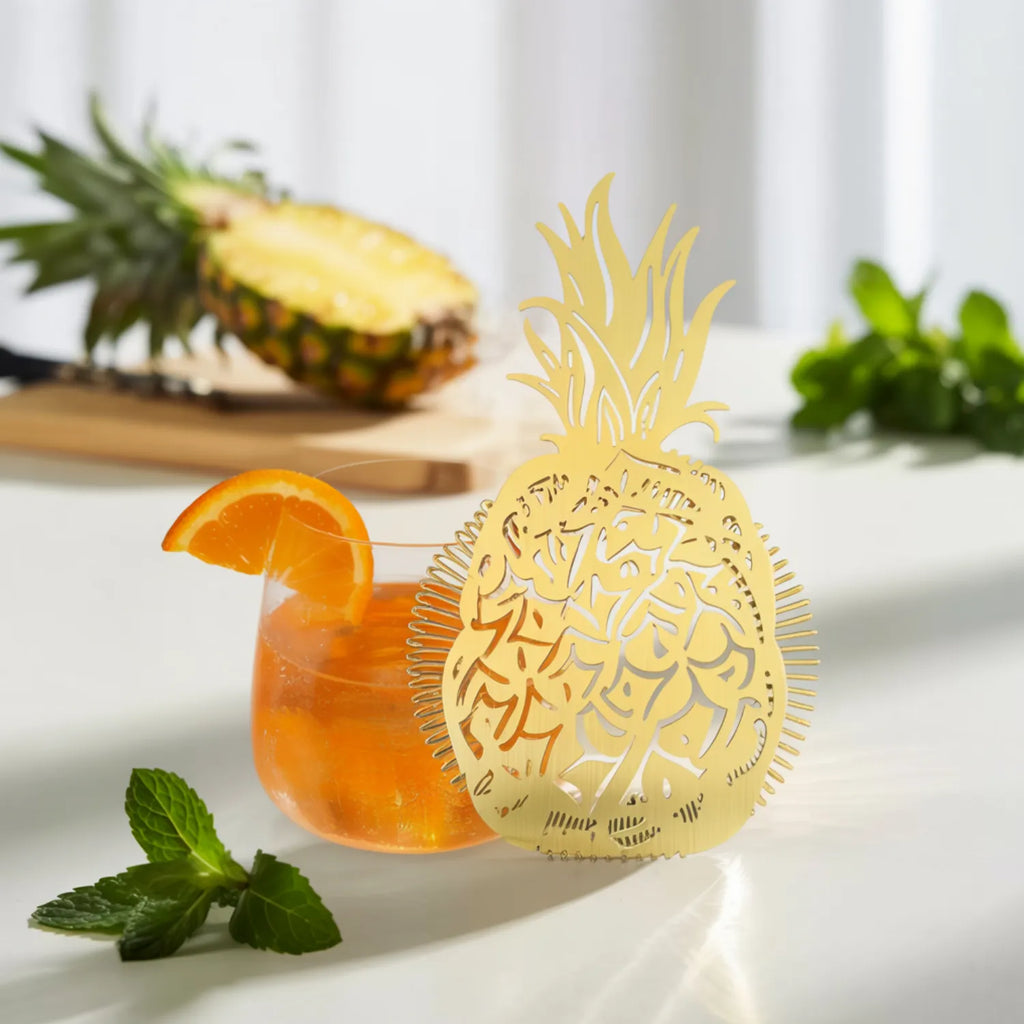 gold pineapple strainer next to a cocktail