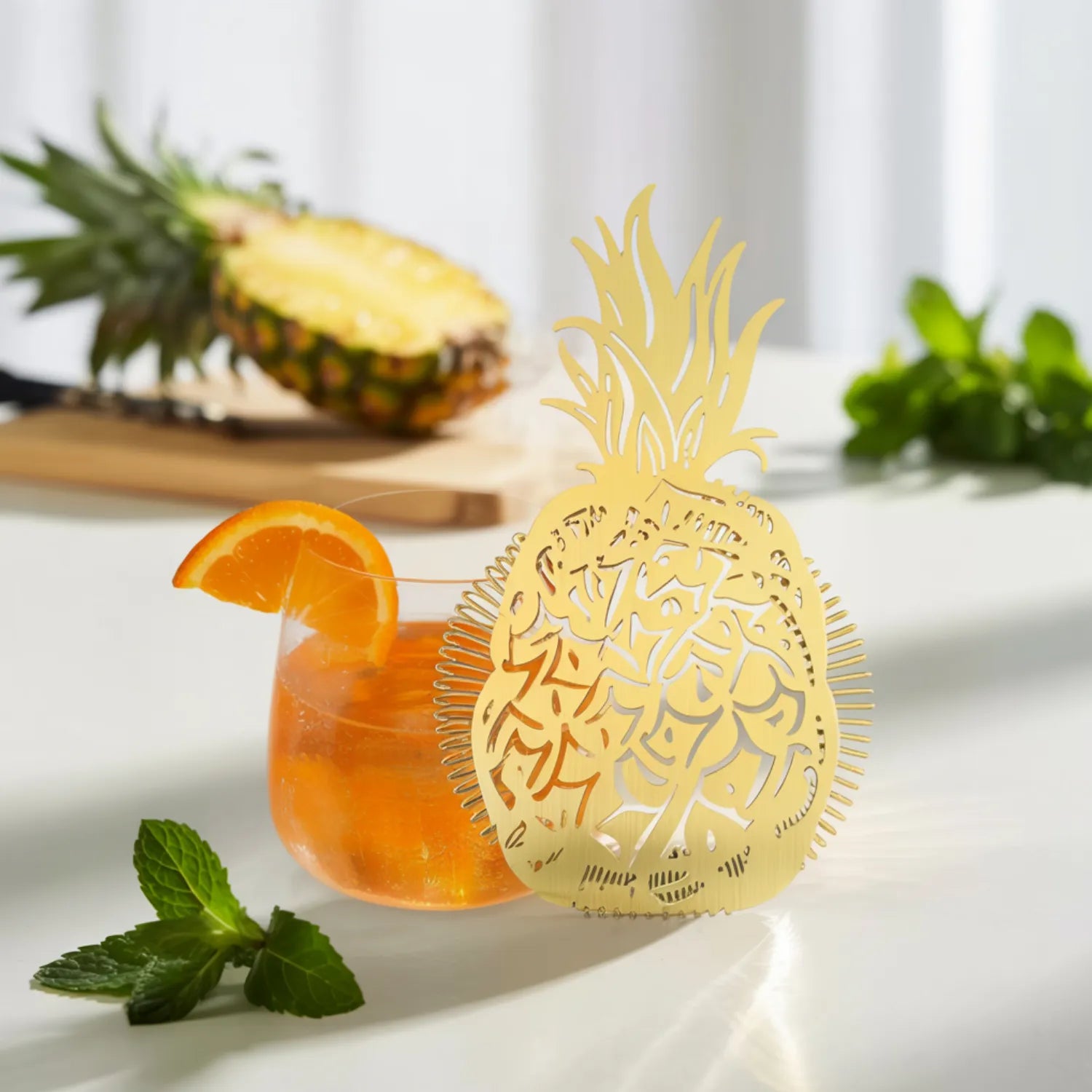 gold pineapple strainer next to a cocktail