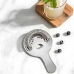 Hawthorne strainer next to a cocktail