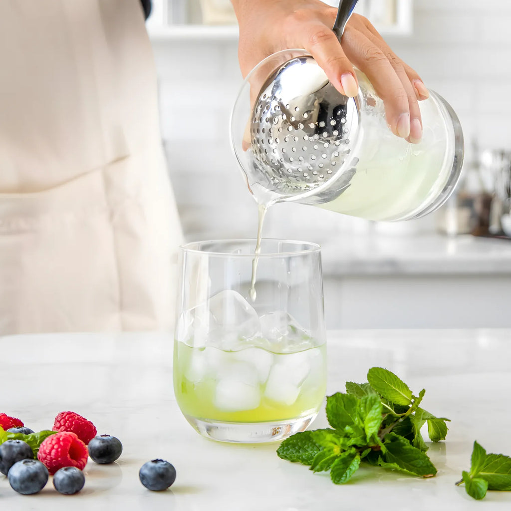 Bartender straining cocktail with a Julep strainer