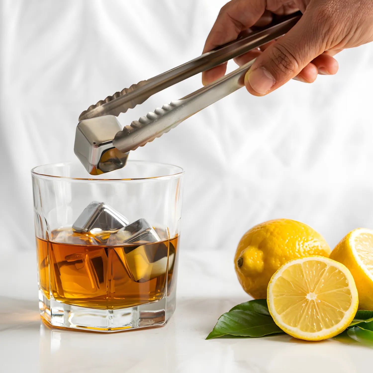 ice tongs holding a stainless steel ice cube