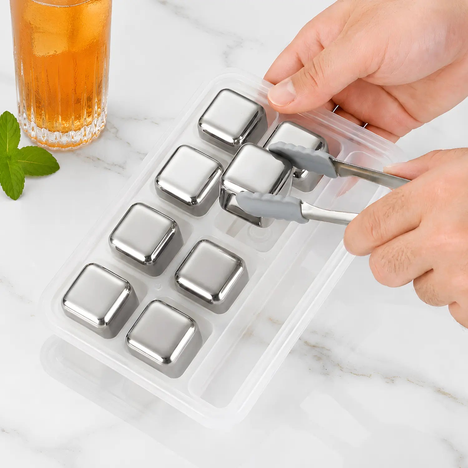 use ice tongs to pick up a stainless steel ice cube
